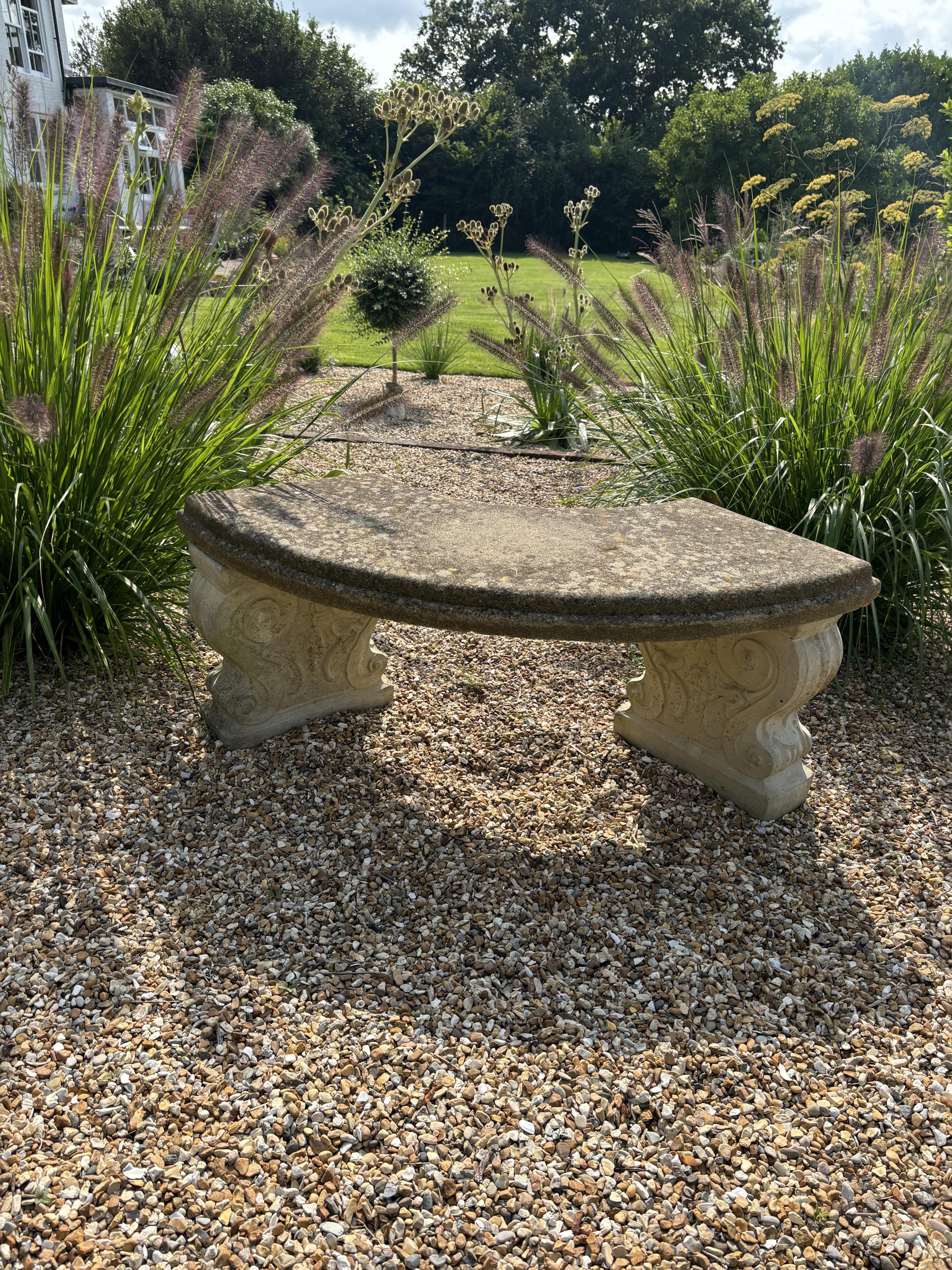 Two reconstituted stone benches, one curved, width 110cm, height 40cm, the other straight, width 114cm, height 44cm. Condition - both weathered, otherwise good condition